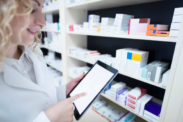 Medical professional standing near medicine shelf while holding tab