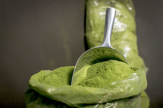 green kratom powder on a stainless scoop